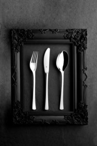 WMF cutlery in a black baroque frame on stone WMF cutlery in a black baroque frame on stone